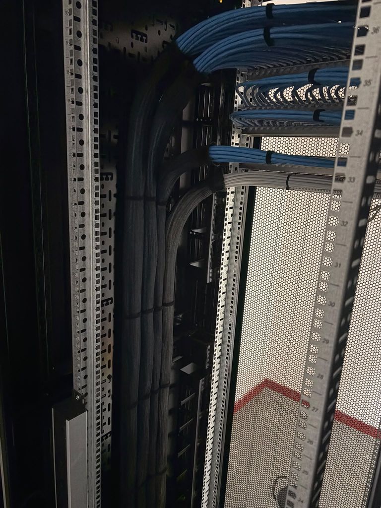 Sleeved looms rising through vertical cable management to the panels above