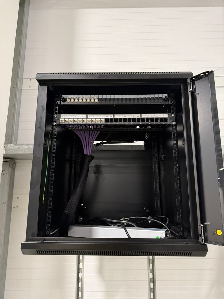 Wall-mounted cabinet with copper patch panels and a sleeved Cat6 loom dressed in